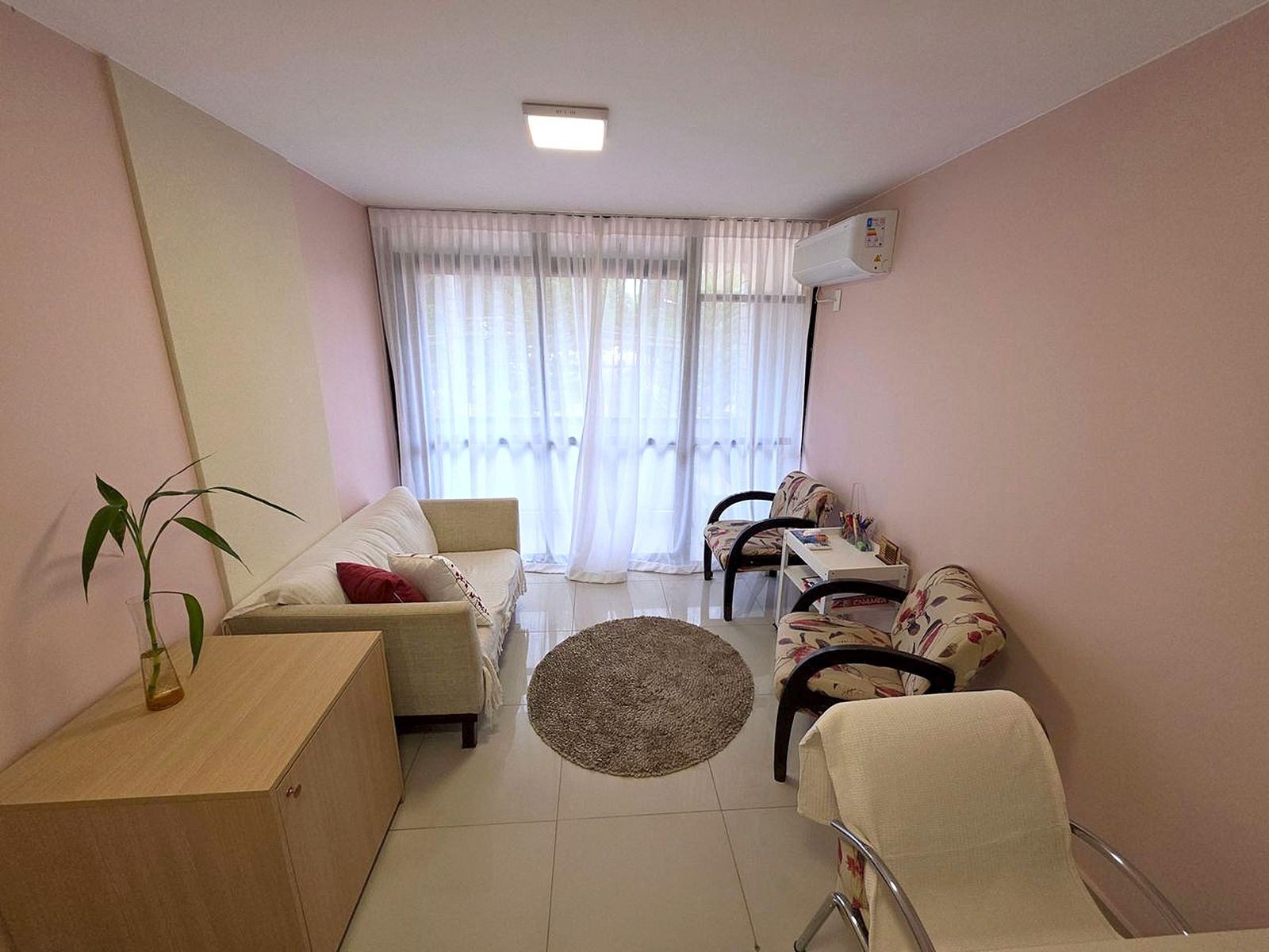Sala de atendimento com sofá, poltronas e janelas amplas
